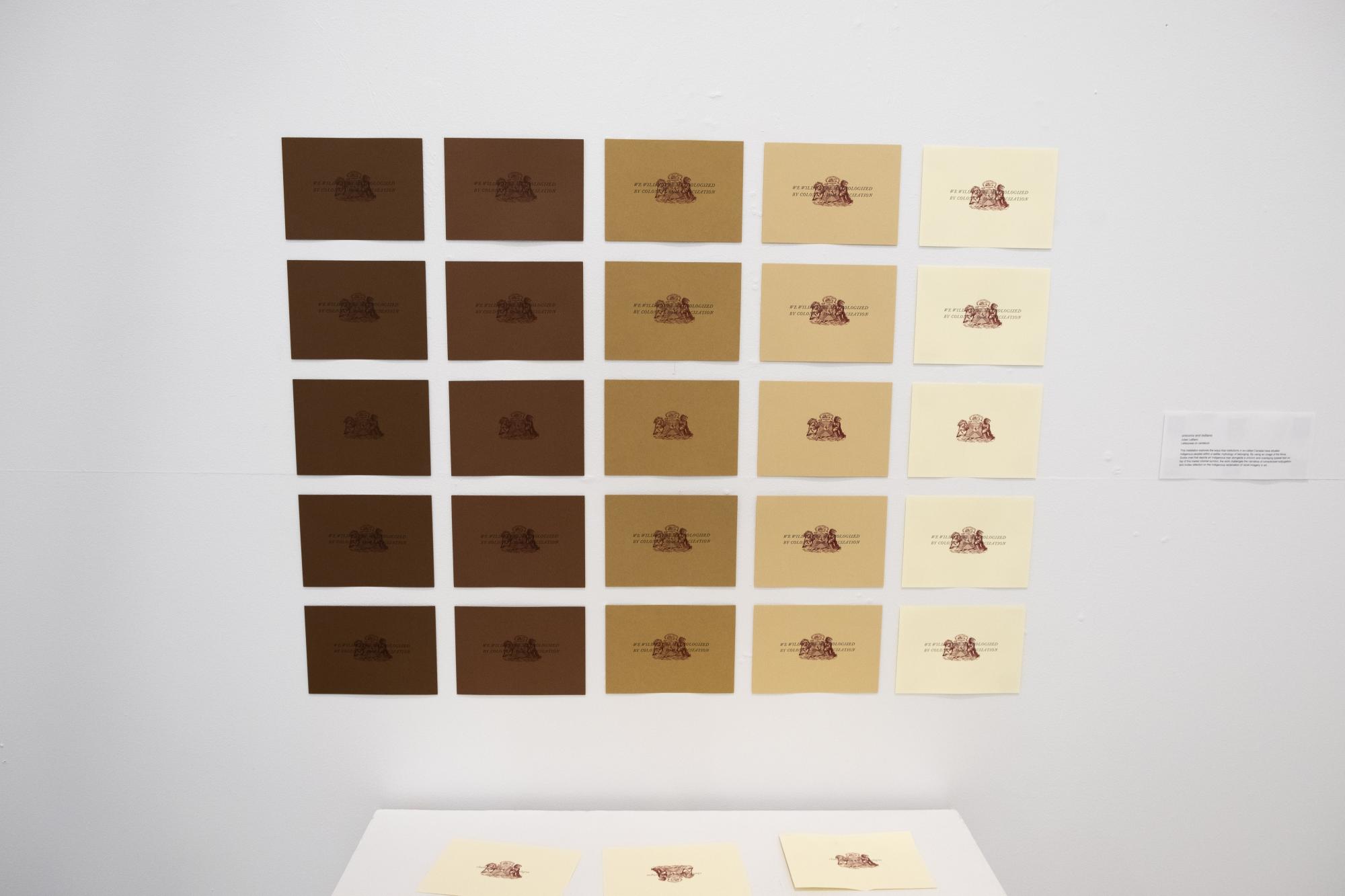 a grid of prints aligned on the wall in a gradient of skin tone colours, starting with dark brown on the left column and moving to white in the furthest right column