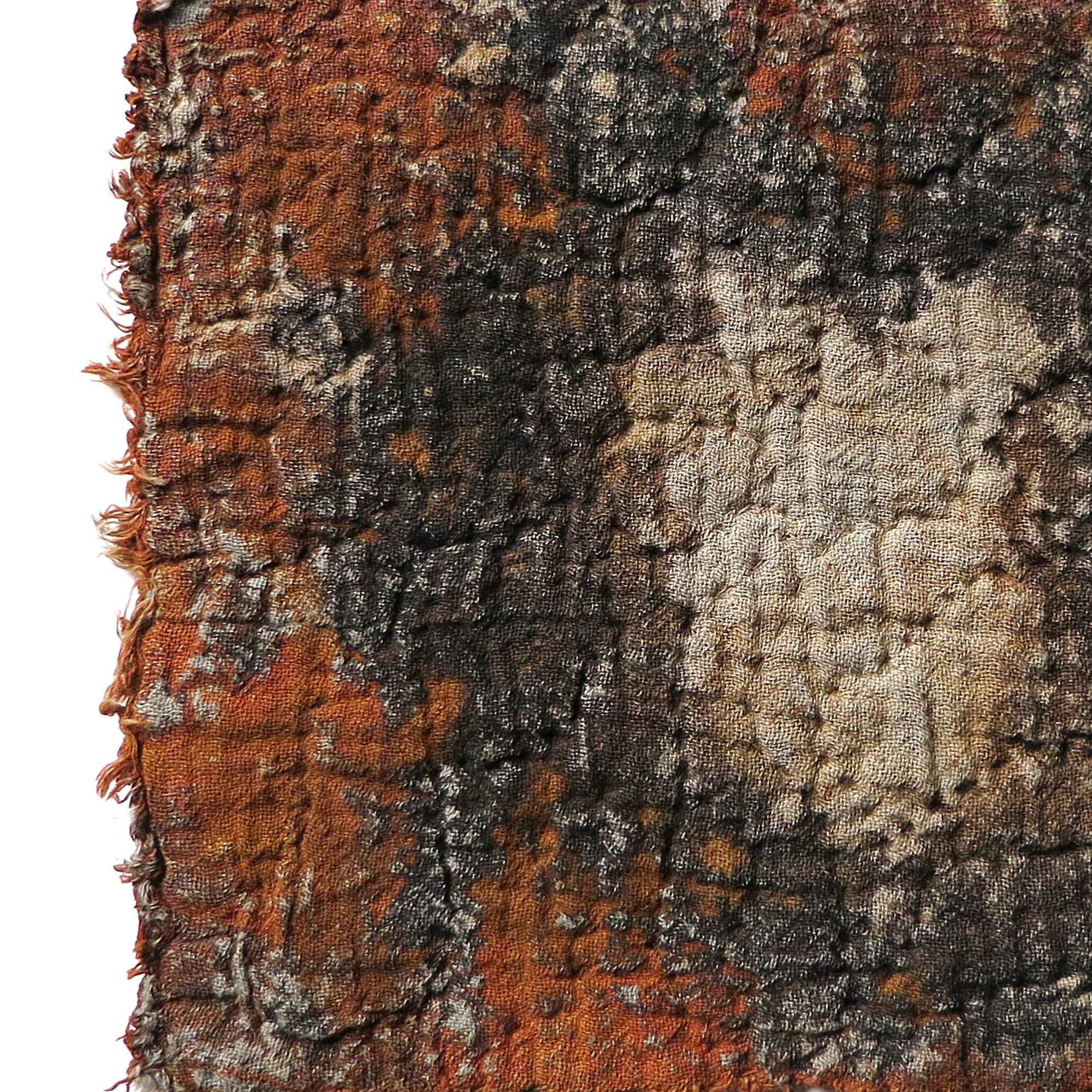 close up detail of a dyed textile with red, blacks and beiges. 