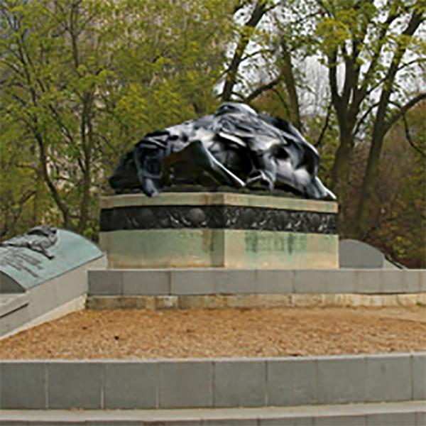 a statue of King Edward 7th riding a horse melted into a pile of twisted black iron on a granite pedestal in a park.