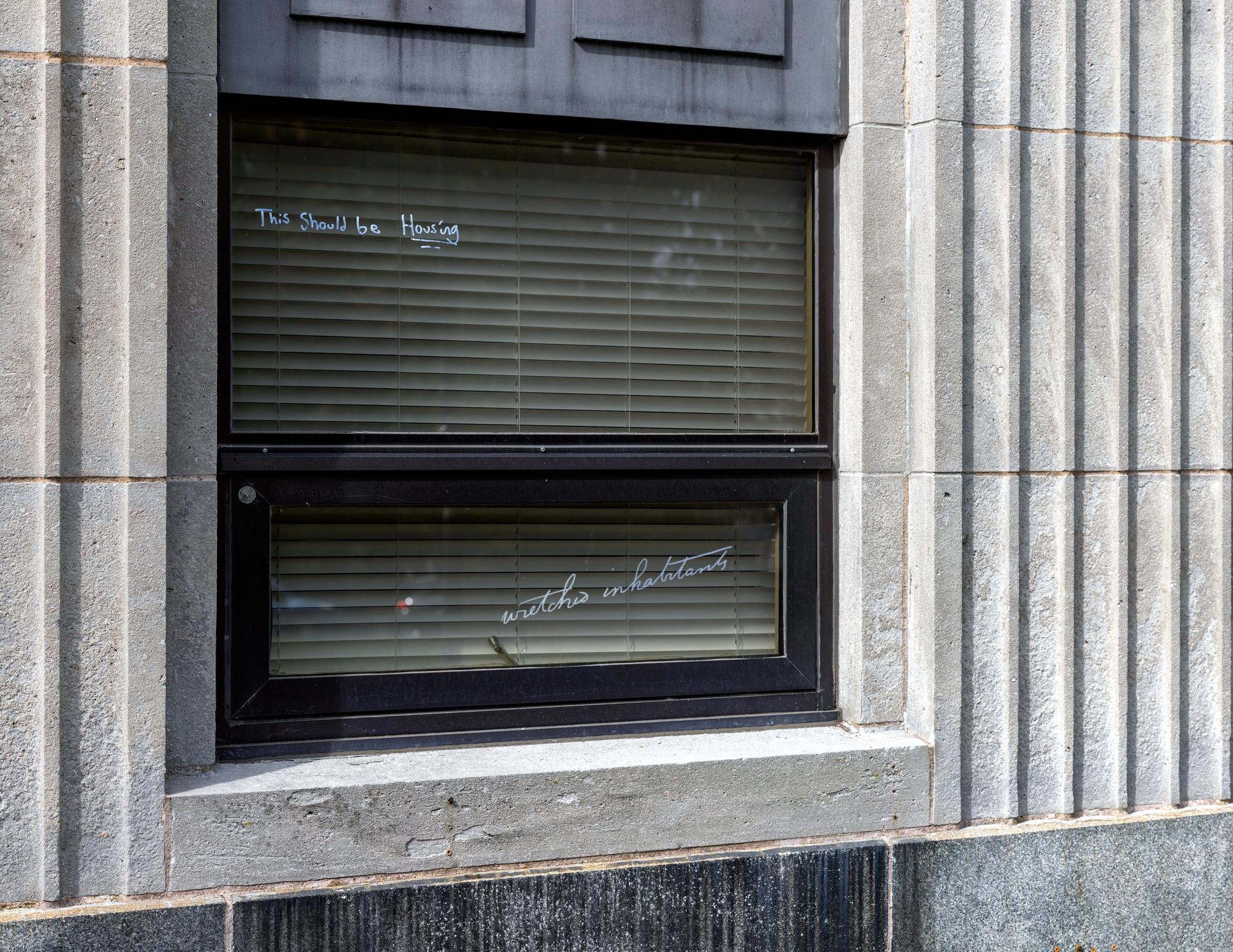 Windows of the old Halifax Memorial Library, writing on the windows read "this should be housing"
