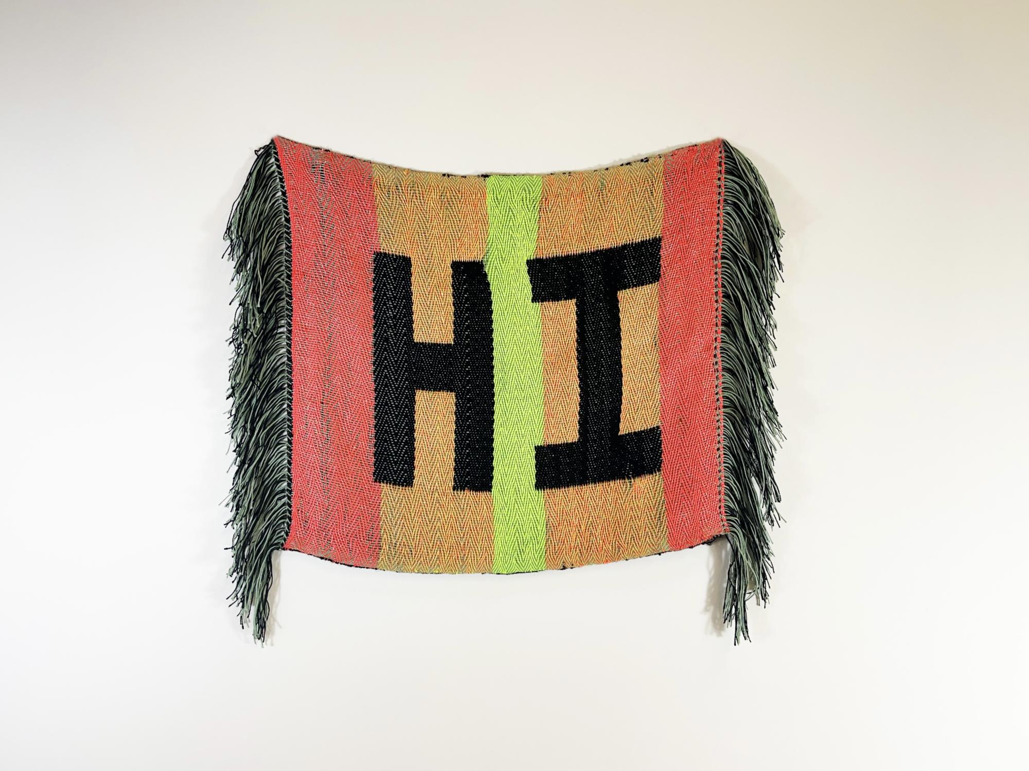 A bright orange, lime green and orange weaving with the word "HI" in black in the middle