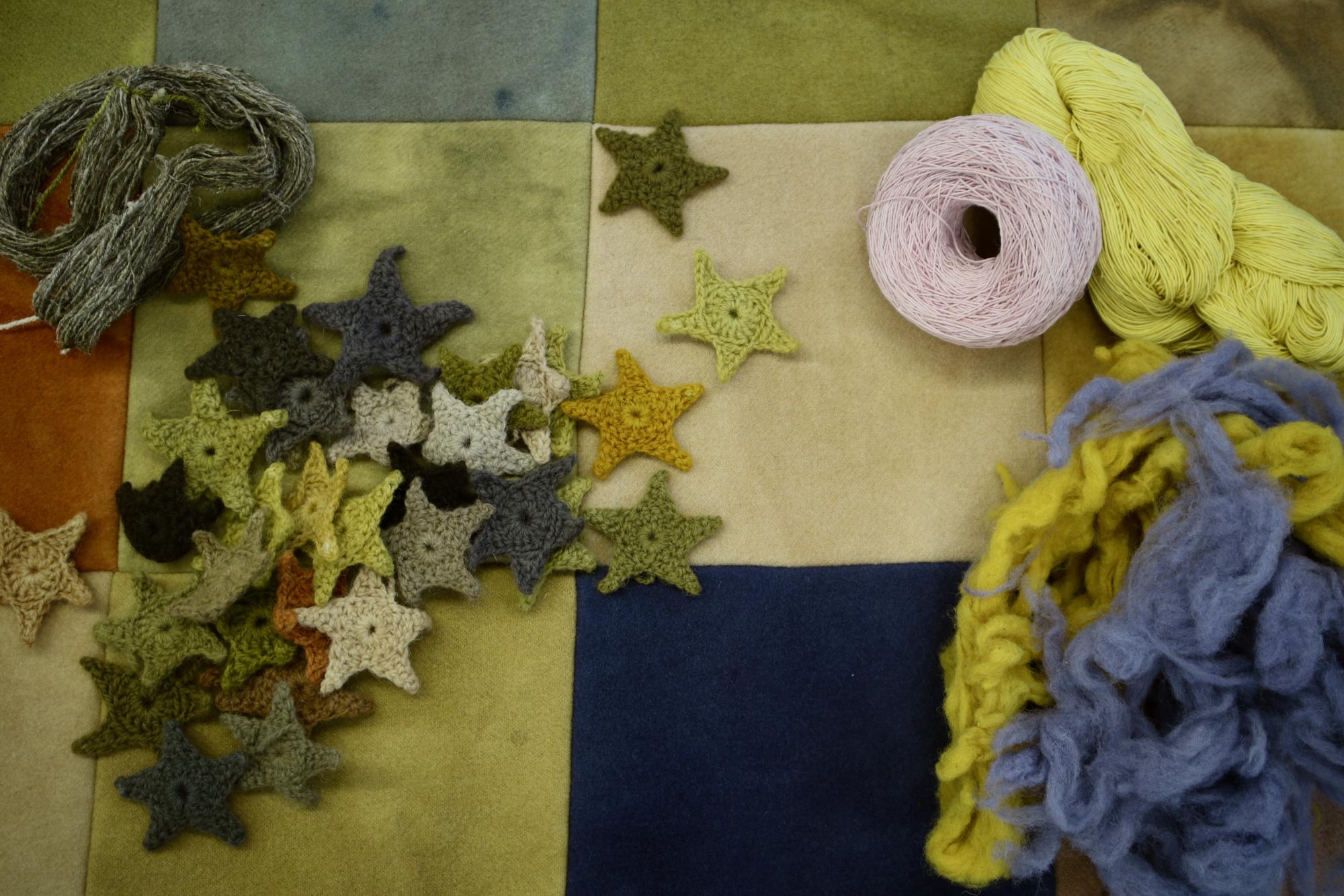 A naturally dyed wool quilt, accompanied by crocheted stars, yarn, and fibres. Including a handspun skein of nettle yarn.