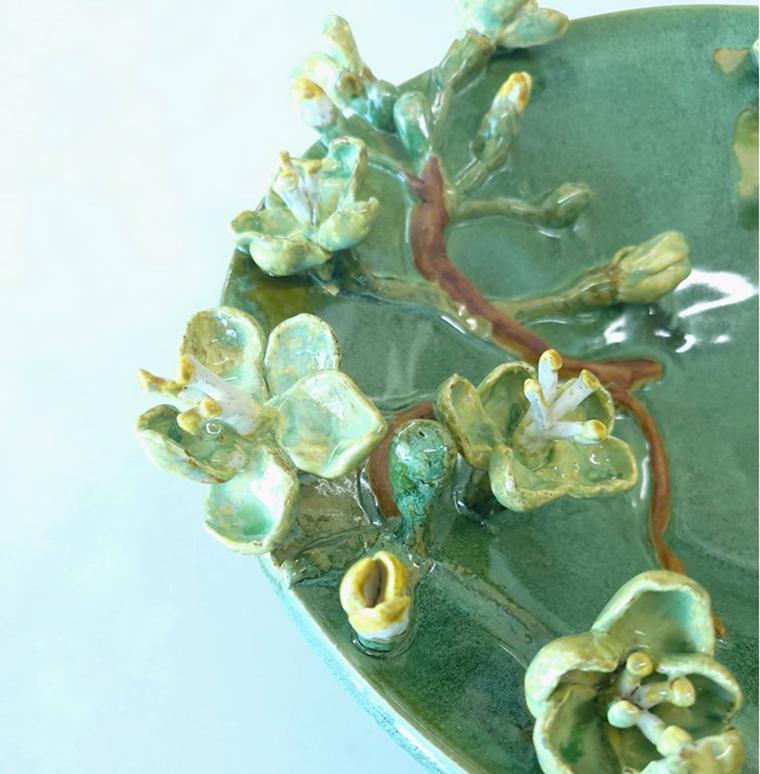 A large green ceramic plate with flower blossoms, from a close-up, top view.