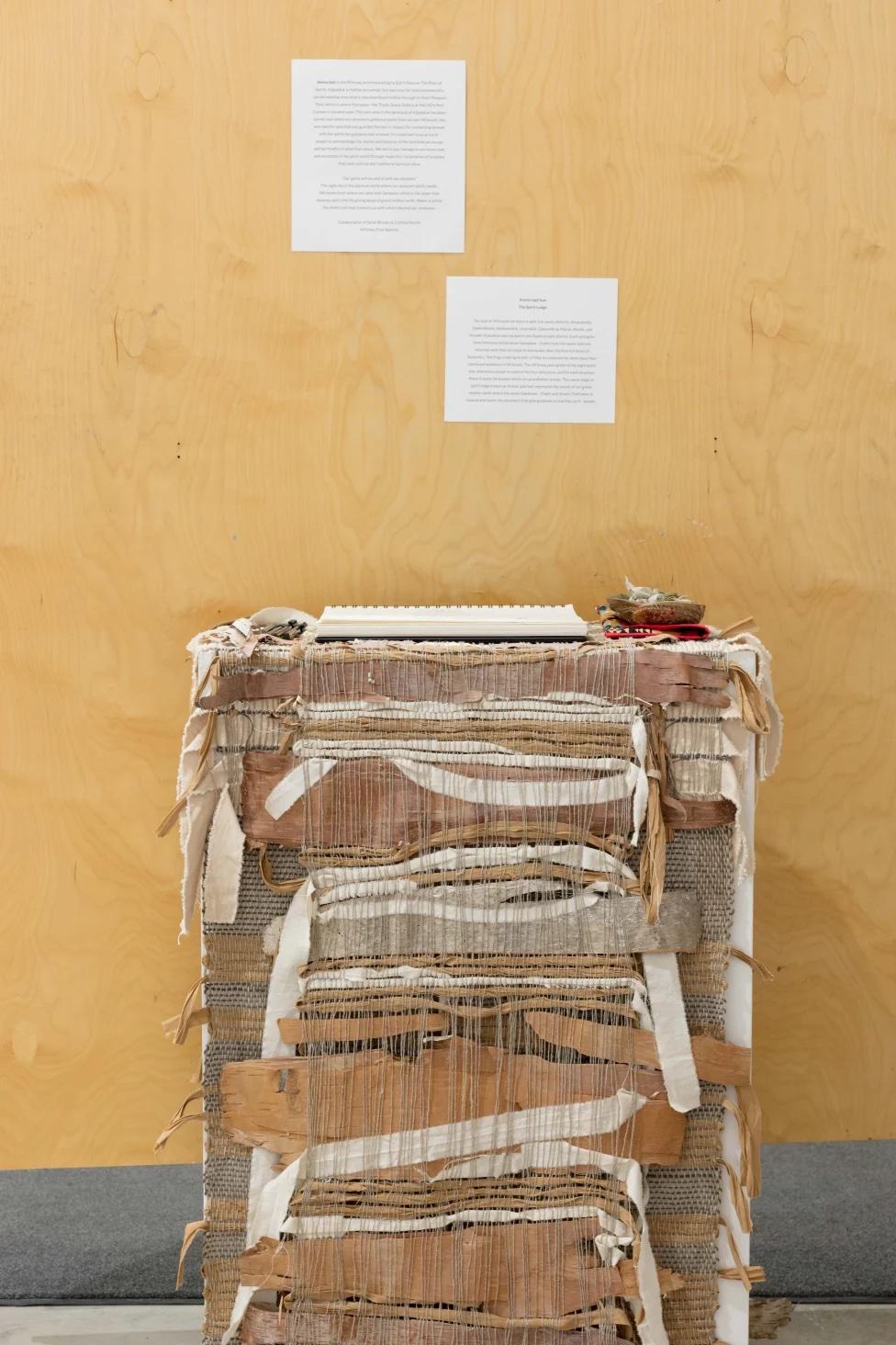 guest book area with plinth that is encased in a woven display of natural materials