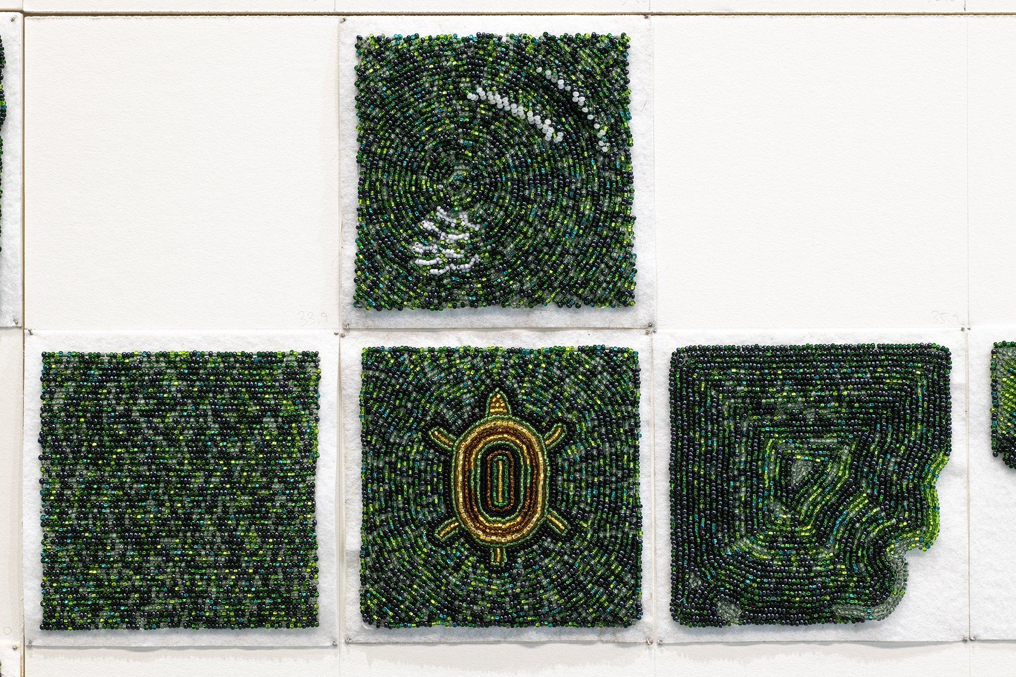 close up of beaded squares made up of small glass seed beads in various shades of green, one square has the image of a brown turtle in the centre