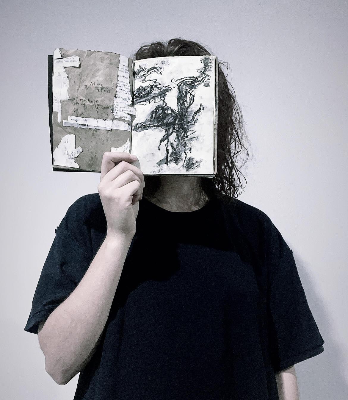 A person holding a book in front of their face, facing out.