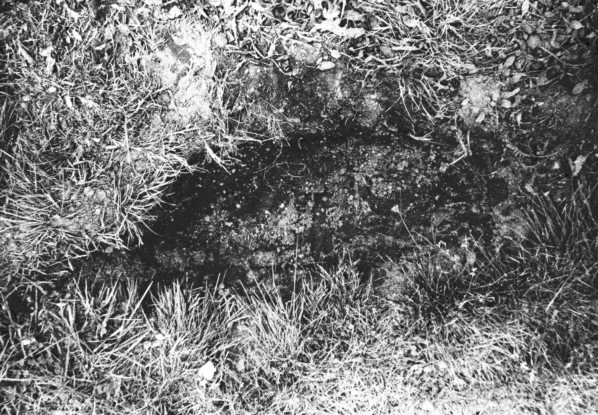 a black and white photograph of a shallow hole dug into the side of a hill.