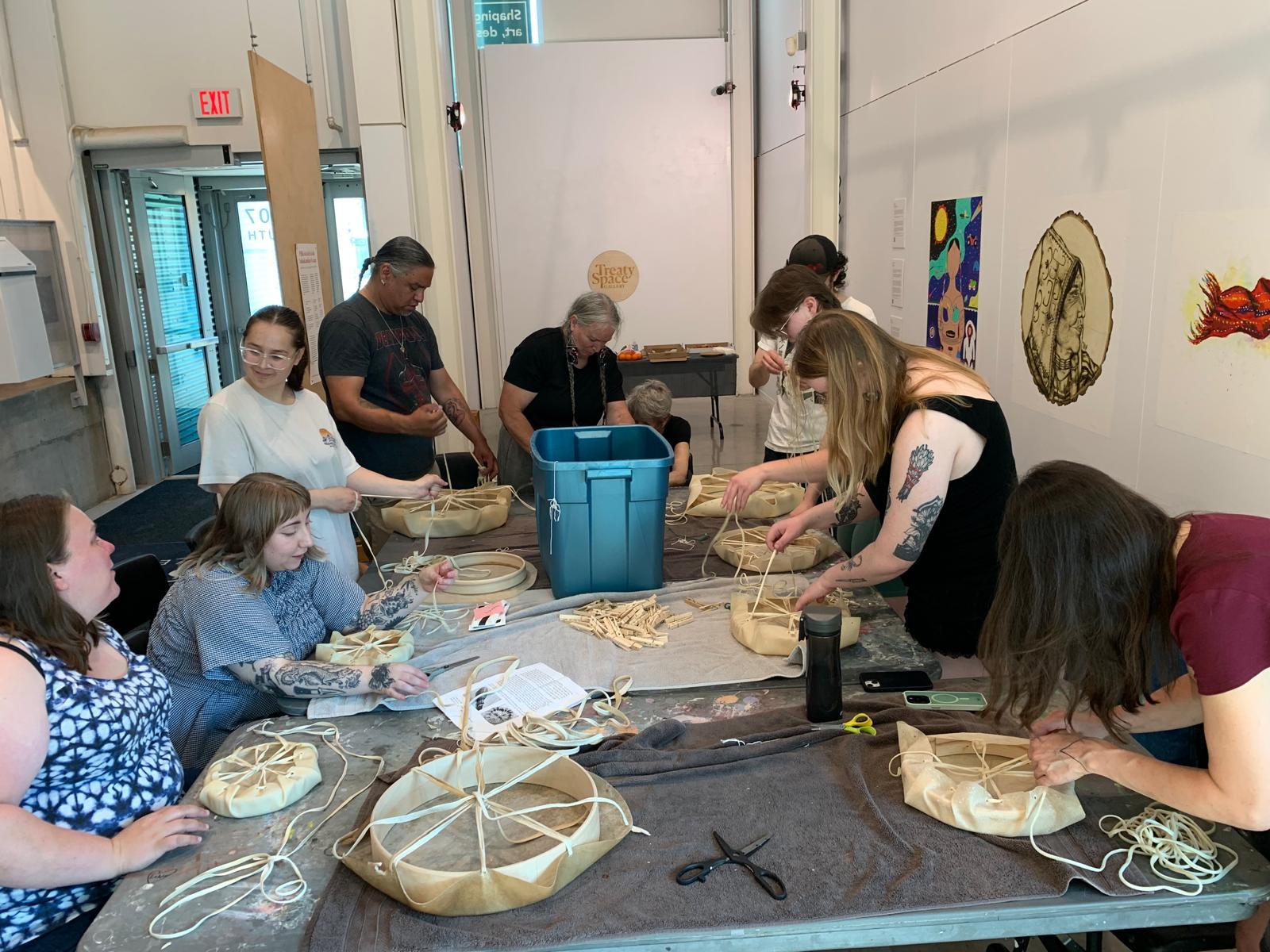 table surrounded by participants making drums