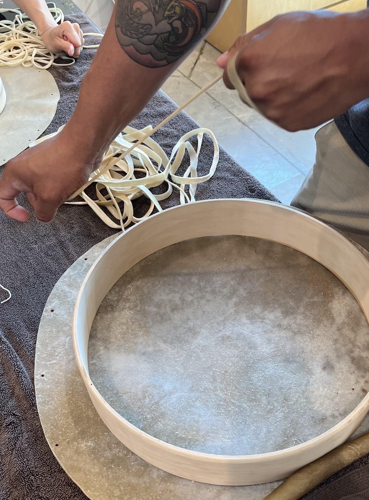 white ash round frame laying on rawhide while lace is being weaved