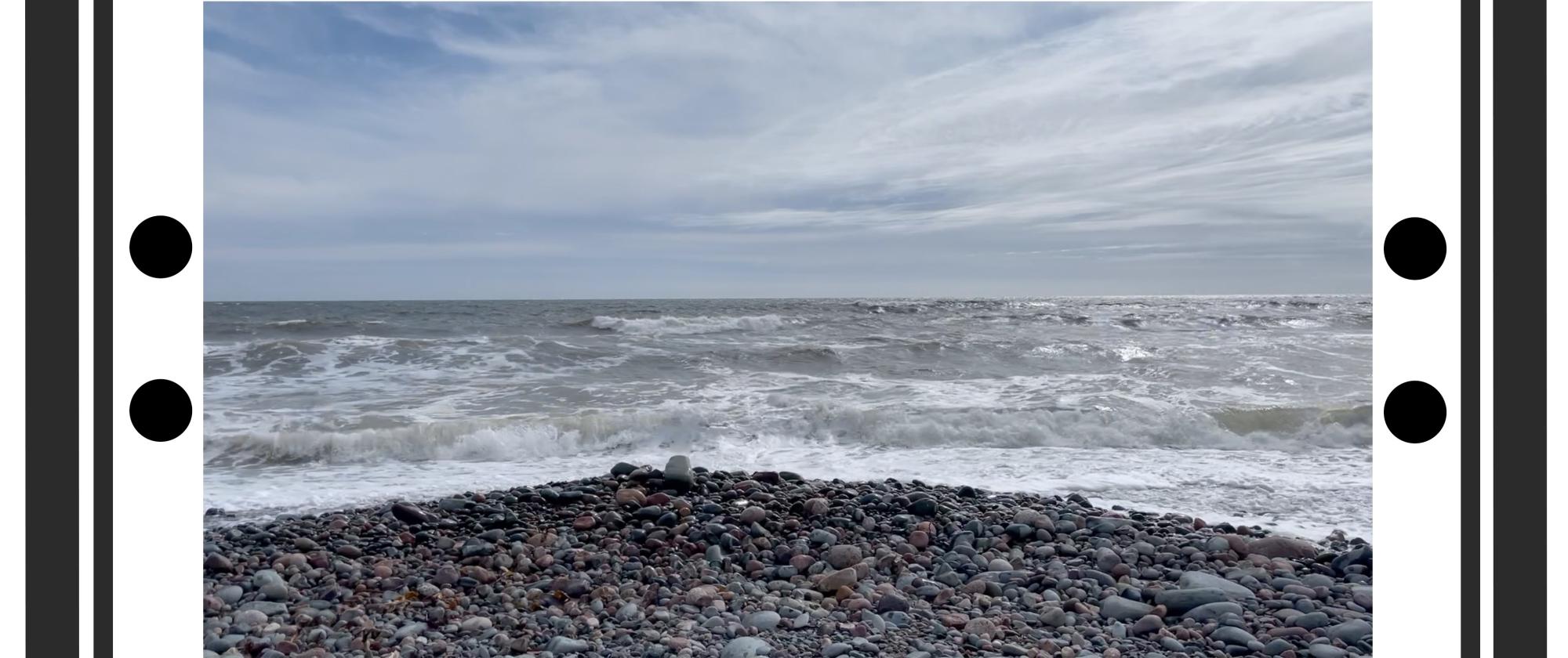 photograph of a rocky shore and ocean waves with black "repeat" music symbol on either end