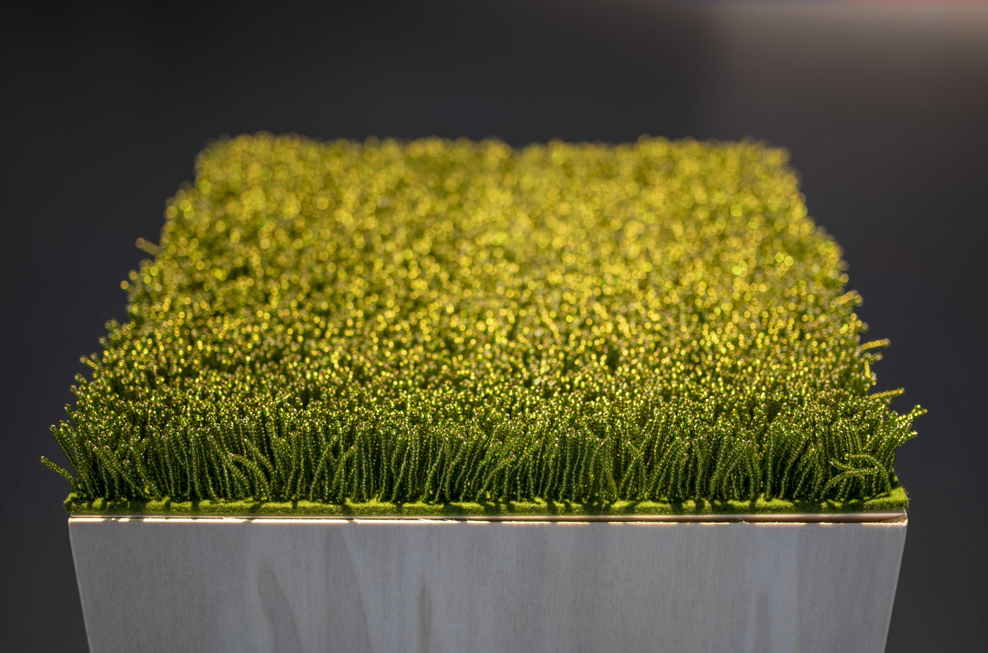 close up photo of hundreds of green glass beads strung in small lines to look like grass