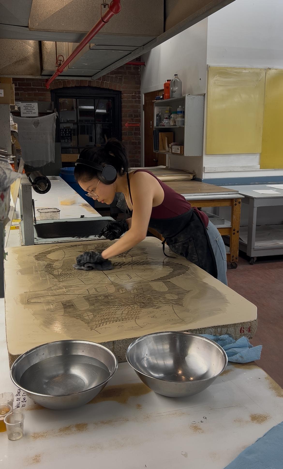 Czarina hunched over, wiping a litho stone.