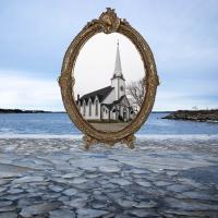 An ornate vintage frame holding the picture of an old church hovers over the icy shoreline as if frozen in time.