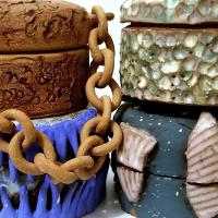 Four ceramic jars, stacked two by two, with various colours, patterns, and textures. A chain hangs down from one of the jars.