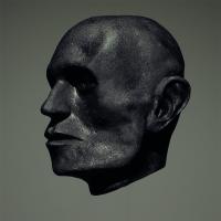 A black painted sculpture of a human head on a grey background.