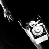 A B/W, inverted photo of hands reaching toward each other and another holding a speaker.