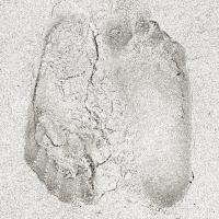 A square, black and white image portrays two footprints in the sand, each going in the opposite direction but very close together. Each imprint slightly effecting the structure of the other