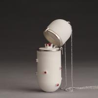 A white capsule-shaped locket pendant with a silver chain stands on a gradual grey background.