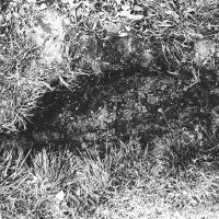 a black and white photograph of a shallow hole dug into the side of a hill.