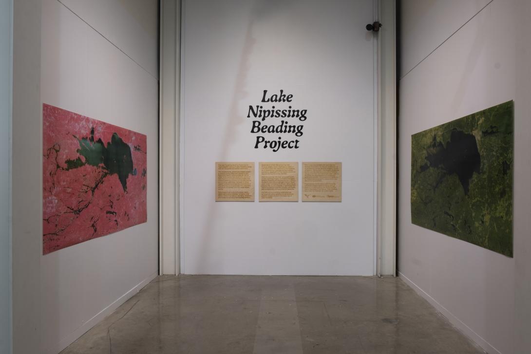 3 walls of a gallery with large maps on two walls and vinyl text reading "Lake Nipissing beading project" on the centre wall. 